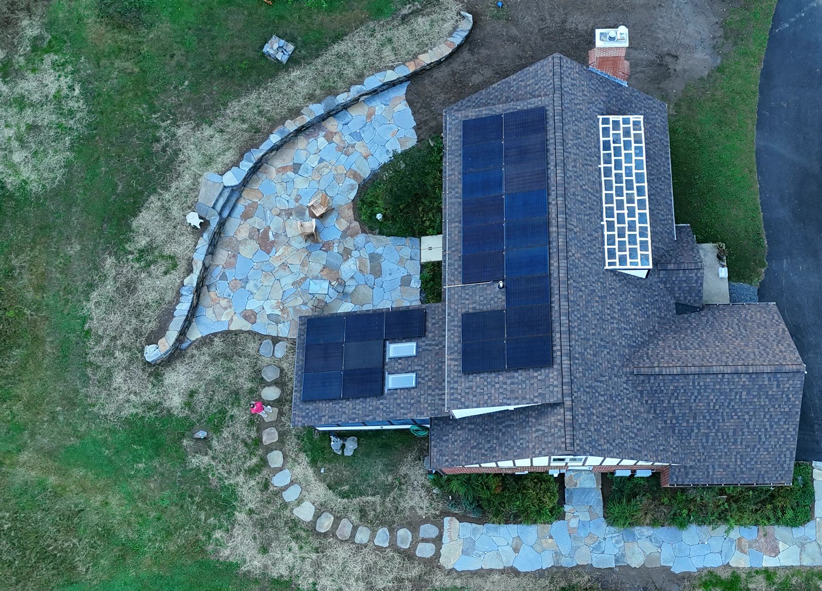 Finished stone patio, curved wall and stepping-stone path wrapping a house, from directly above